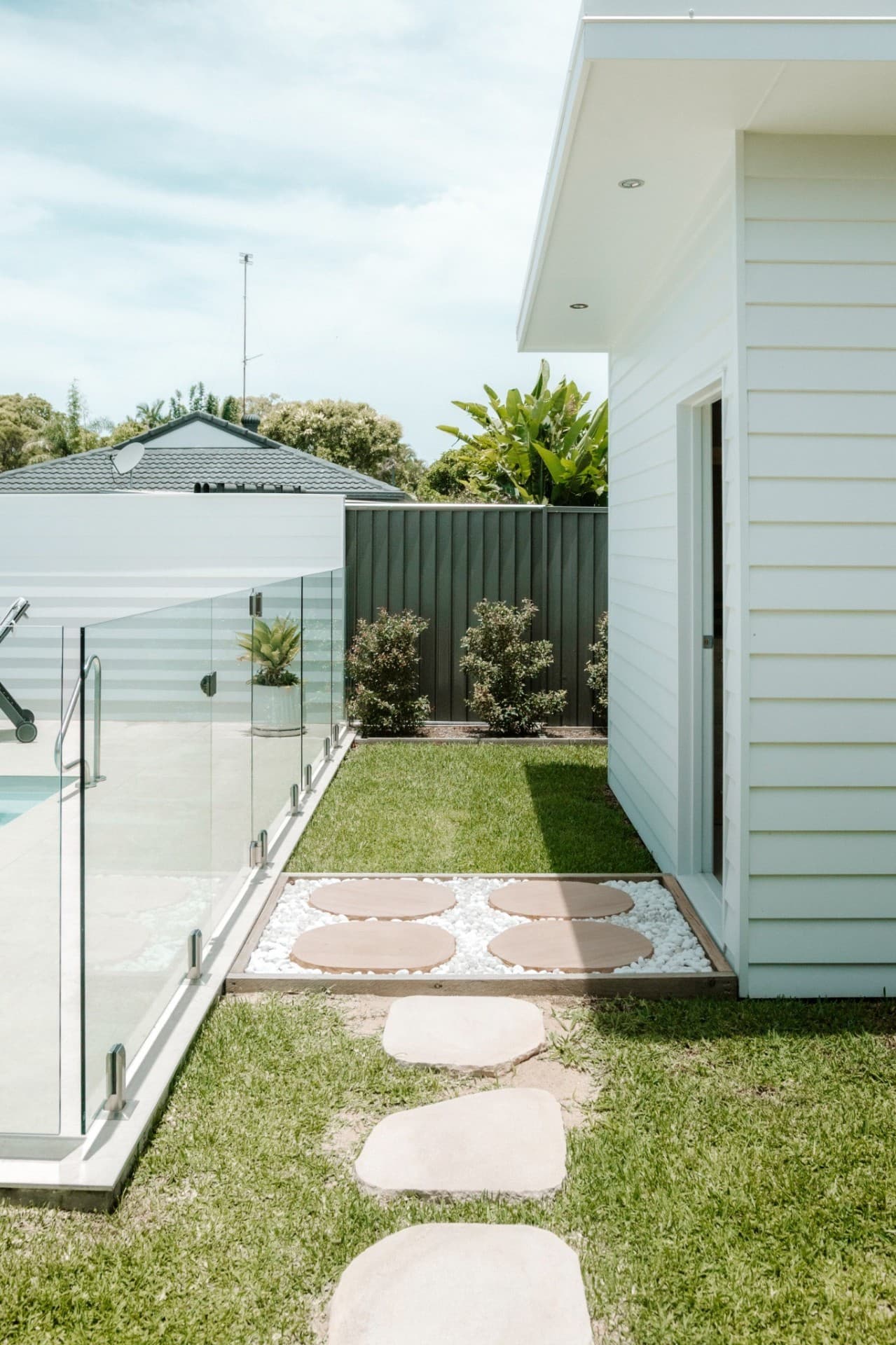 Mermaid Waters poolside garden with stepping stones, glass pool fence and weatherboard cladding.